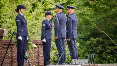 Twee militairen salueren tegenover een krans op een standaard. Daarnaast staan twee andere militairen.