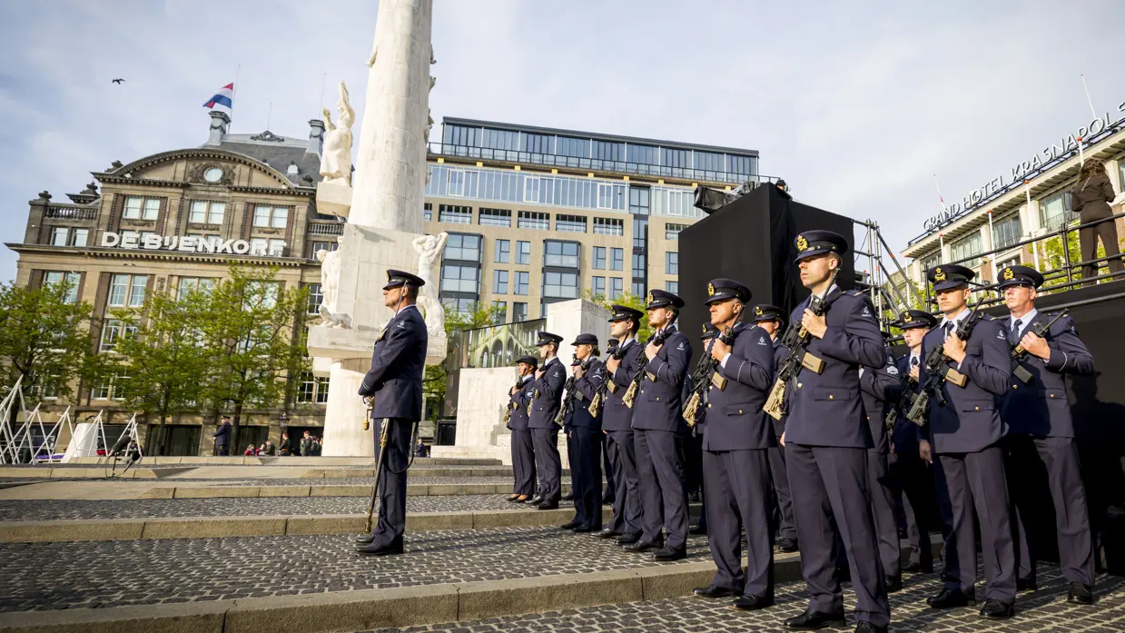 Een detachement luchtmachtmilitairen staat opgesteld naast het Monument op de Dam. In de achtergrond het winkelpand van de Bijenkorf.