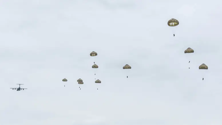 Parachutisten dalen met geopende parachutes neer boven de Belgische heide tijdens oefening Versatile Guard 