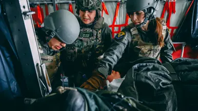 Drie militairen behandelen een patiënt aan boord van een vliegtuig.