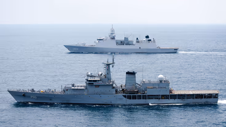 Op de voorgrond vaart een Indiaas marineschip, daarachter de De Ruyter.