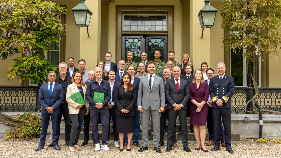 Groepsfoto van poserende werkgevers, reservisten en de staatssecretaris 
