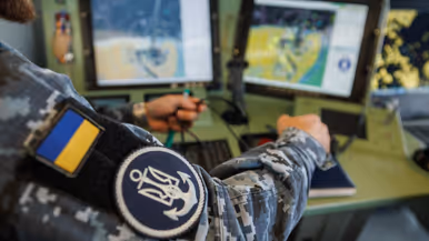 Een militair op de brug, een militair kijkt aan dek door een verrekijker en een militair bedient apparatuur op de brug.