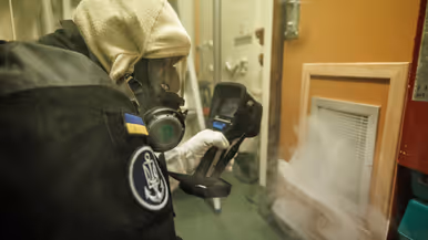Een brandbestrijder controleert rook die uit rooster van een deur komt