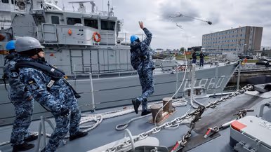 Een militair gooit een tros naar de kade om aan te leggen