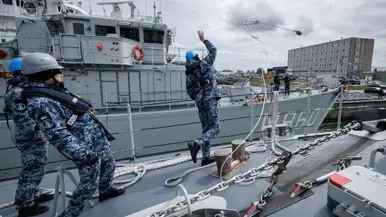 Een militair gooit een tros naar de kade om aan te leggen