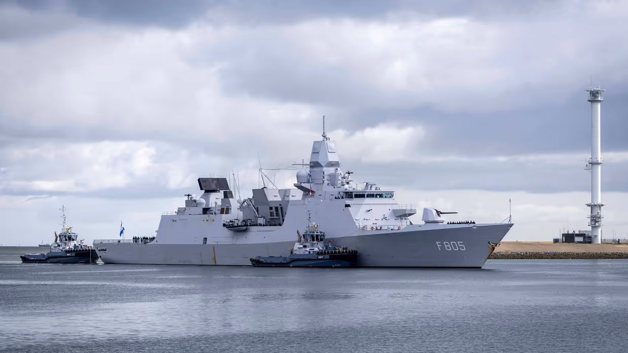 Linkerfoto: twee sleepboten escorteren de Evertsen. Rechterfoto: een marineman hoe de Evertsen richting de kade vaart.