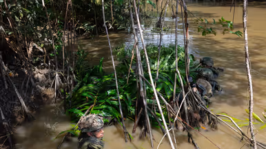 Mariniers houden een drijfpakket in de rivier vast   Marinier legt takken op het drijfpakket 