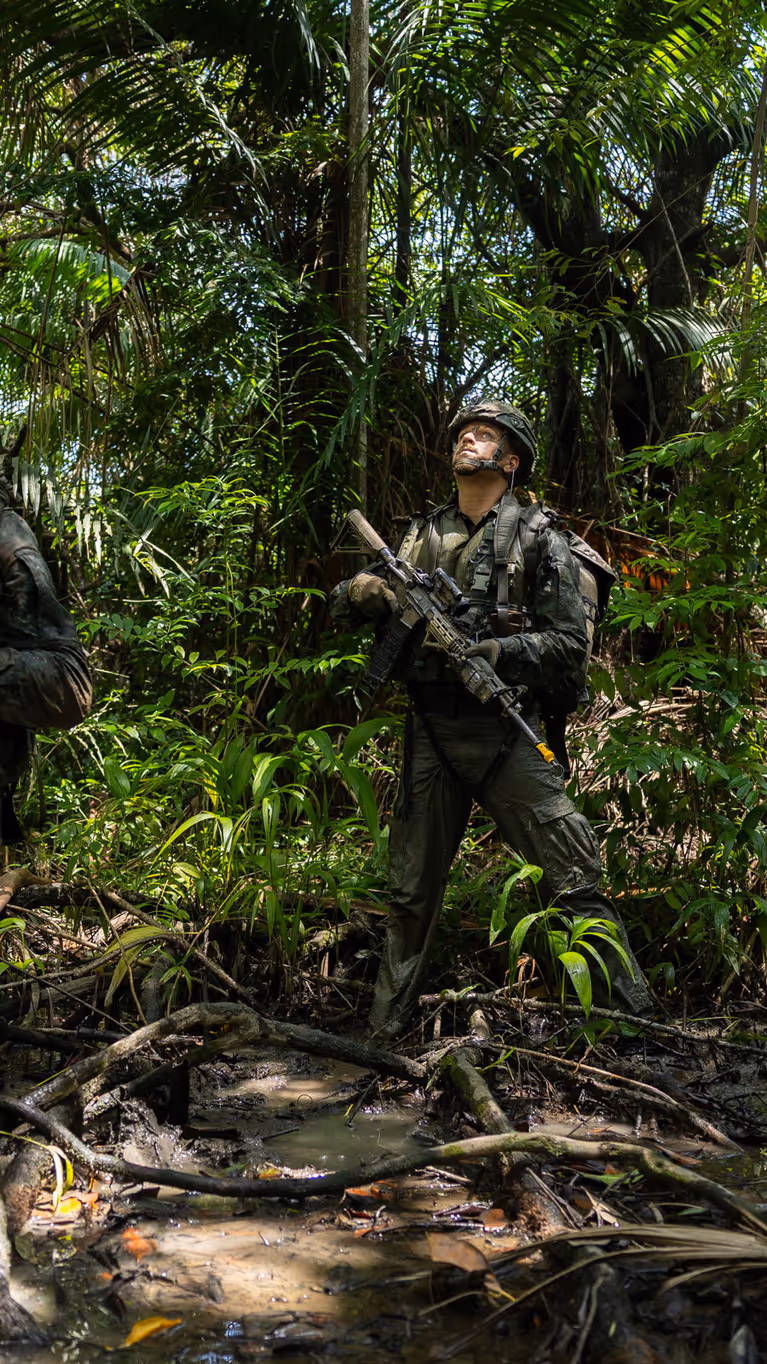 2 militairen lopen op patrouille door de jungle.