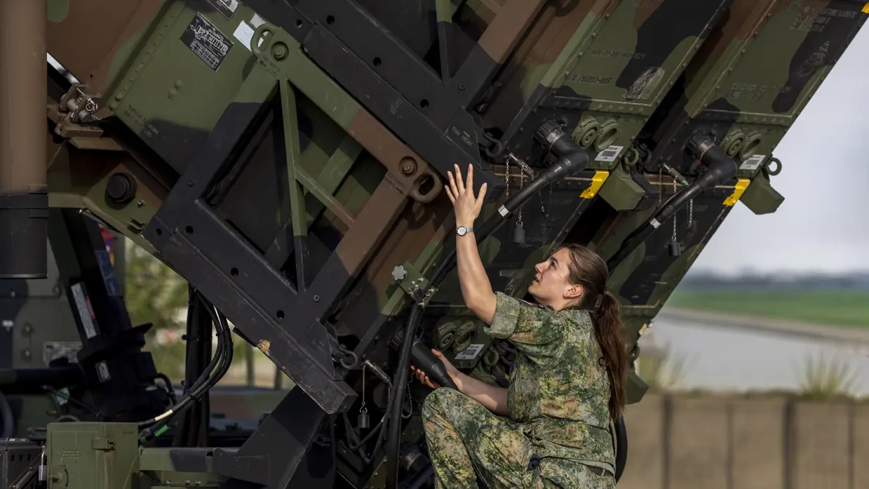 Op de linkerfoto sleutelt een militair aan een generator. Op de rechterfoto voert een militair handelingen uit aan een Patriot-lanceerinstallatie. 