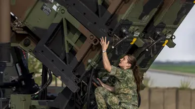 Op de linkerfoto sleutelt een militair aan een generator. Op de rechterfoto voert een militair handelingen uit aan een Patriot-lanceerinstallatie. 