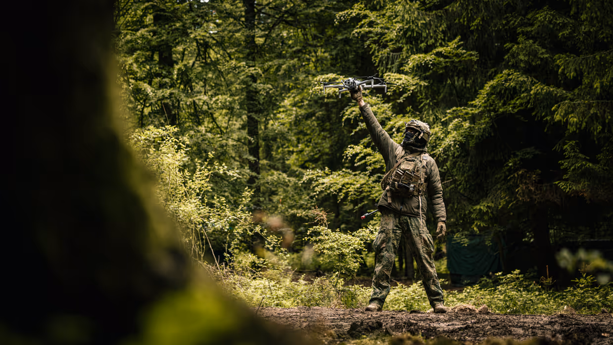 Een militair laat een drone opstijgen in het bos.