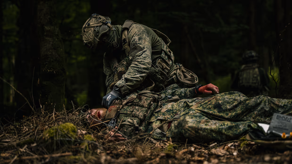 Bij een oefening helpt een militair een gewonde collega tijdens een ZHKH-casus. 