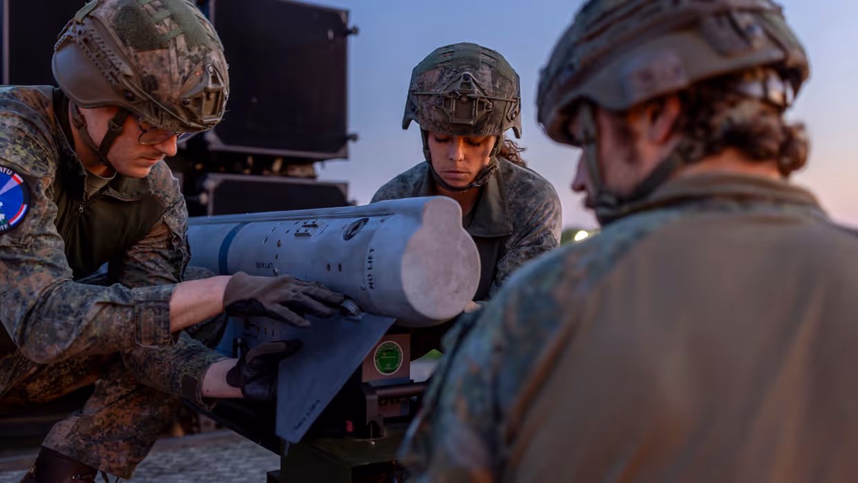 Op de linkerfoto een NASAMS-lanceerinrichting in het avondrood. Op de rechterfoto monteren militairen stabilisatievinnen op een luchtdoelraket.