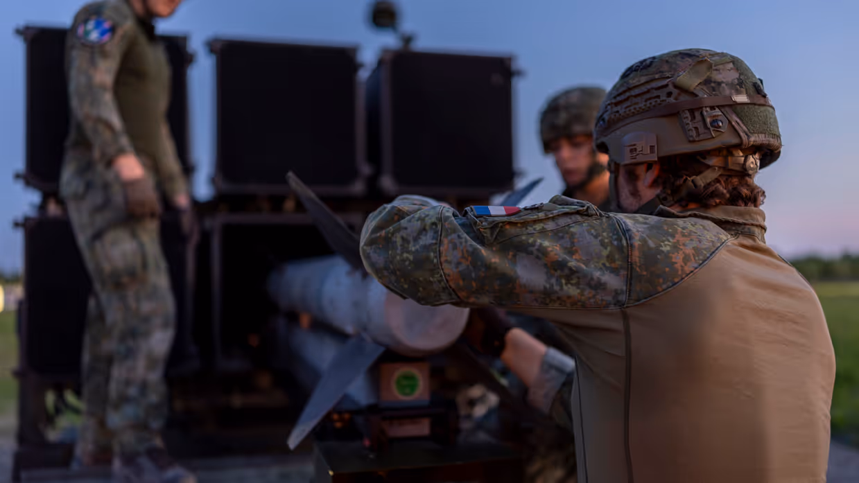 Drie militairen laden een raket in het luchtafweersysteem.