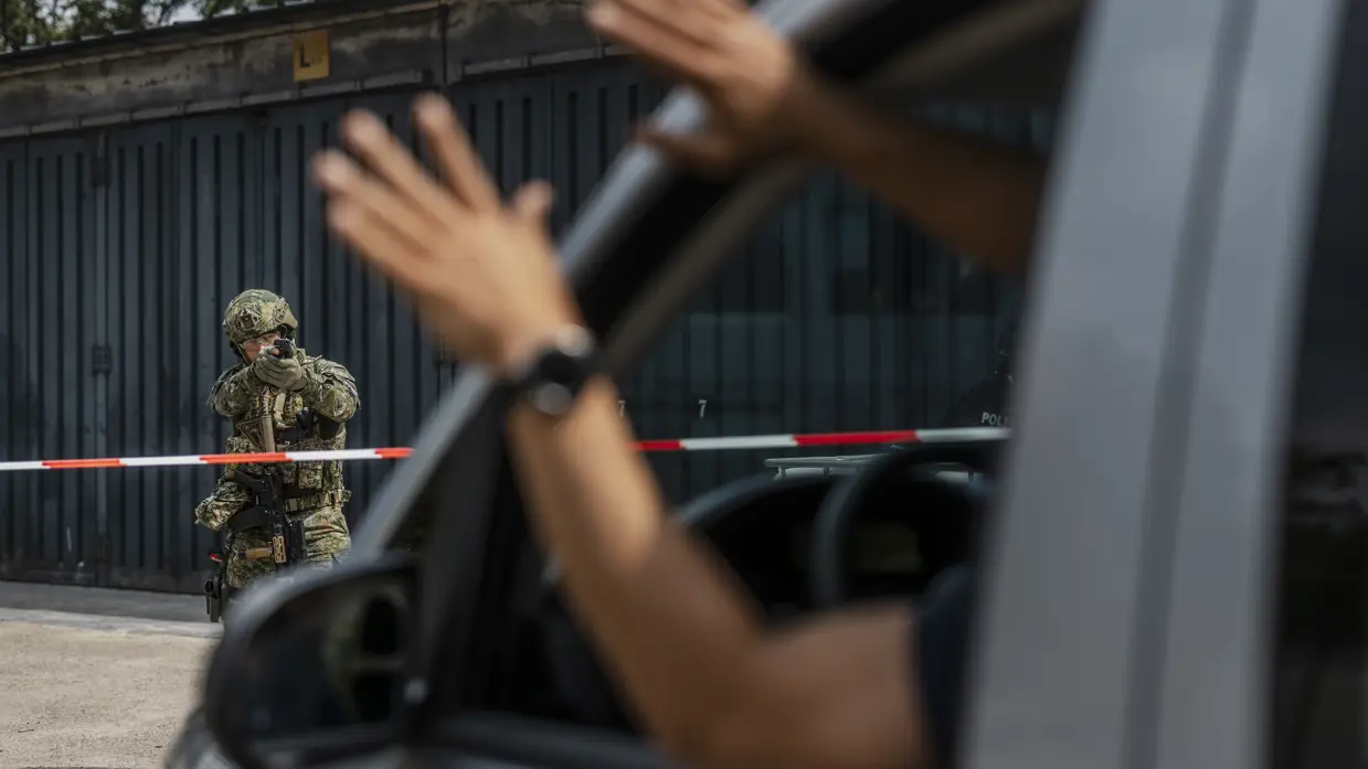 Militair heeft zijn wapen in de aanslag tegenover een auto waar een verdachte persoon zijn handen omhoog steekt.
