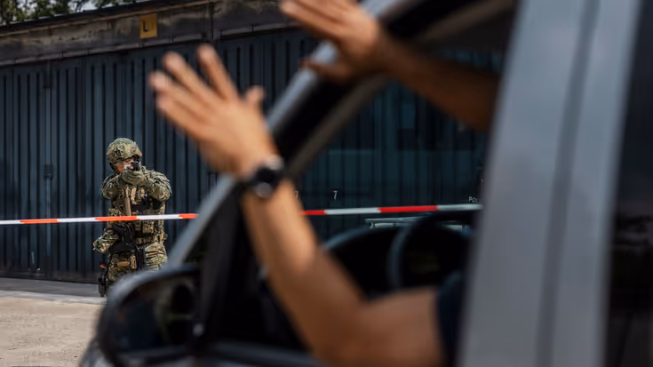 Militair heeft zijn wapen in de aanslag tegenover een auto waar een verdachte persoon zijn handen omhoog steekt.