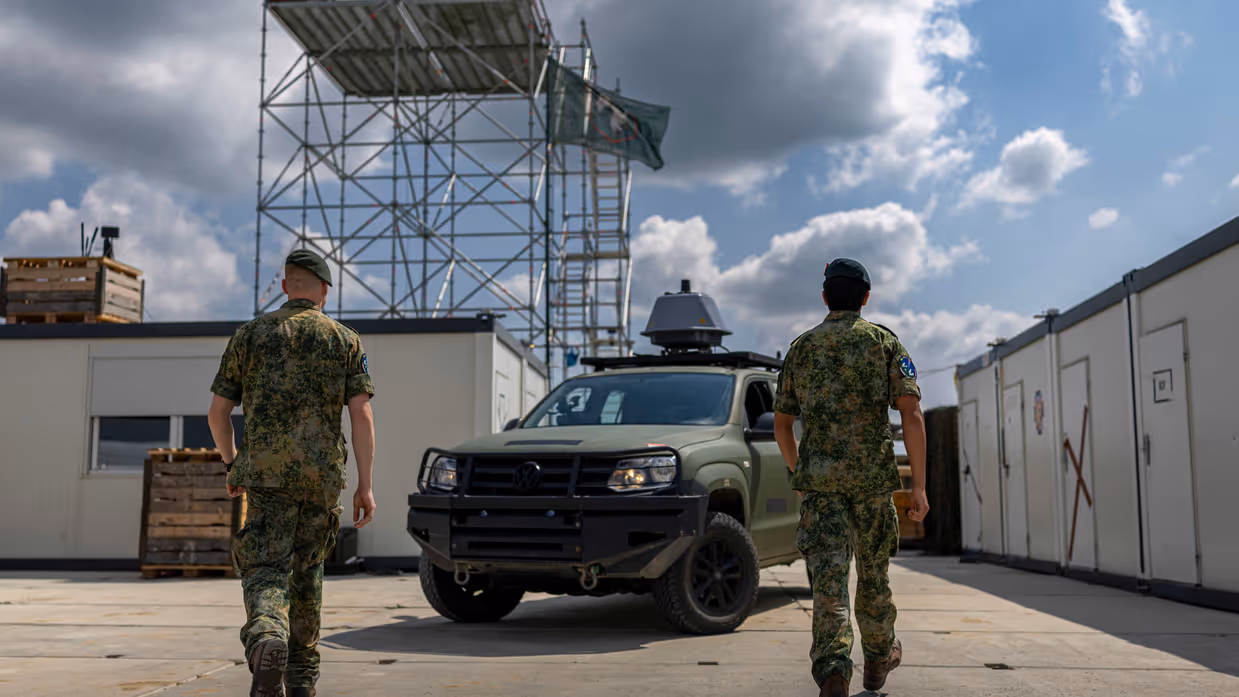 Op de linkerfoto lopen twee militairen naar een Amarok-legervoertuig met daarop een grijze bol. Op de rechterfoto zitten twee militairen in een Amarok-legervoertuig en kijken naar een scherm. 