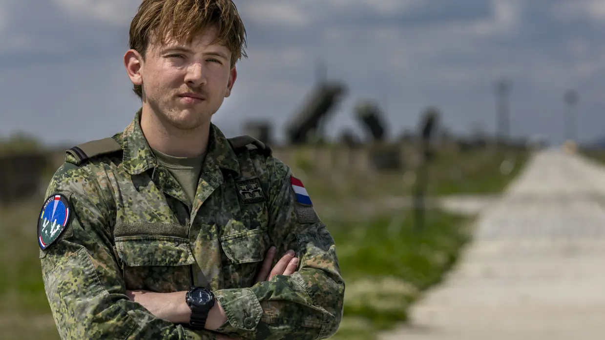 Ronan staat met de armen over elkaar. Op de achtergrond staan Patriot-lanceerinstallaties.
