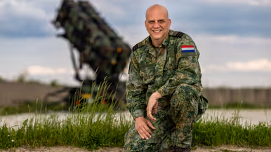 Commandant Van Empel zit gehurkt op één knie.