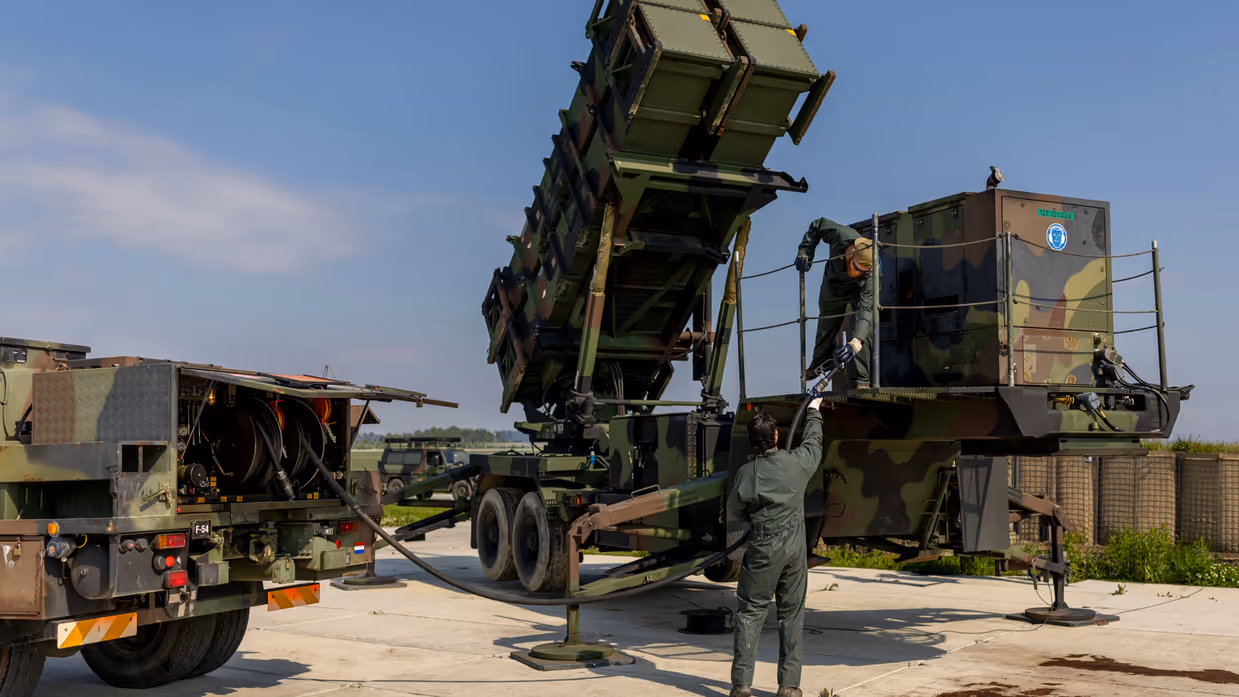 Twee militairen tillen een brandstofslang naar een aggregaat op een lanceerinstallatie.