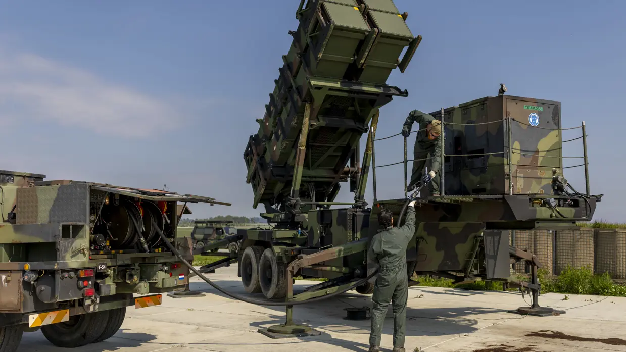 Twee militairen tillen een brandstofslang naar een aggregaat op een lanceerinstallatie.