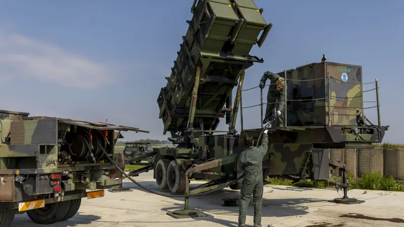 Twee militairen tillen een brandstofslang naar een aggregaat op een lanceerinstallatie.