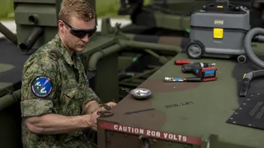 Op de linkerfoto sleutelt een militair aan een wapensysteem. Op de rechterfoto een mouwembleem van de AMDTF.