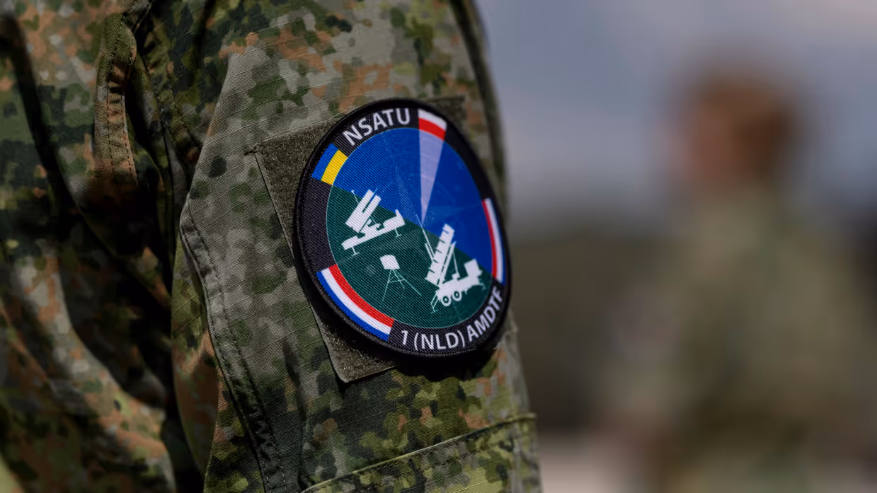 Op de linkerfoto sleutelt een militair aan een wapensysteem. Op de rechterfoto een mouwembleem van de AMDTF.