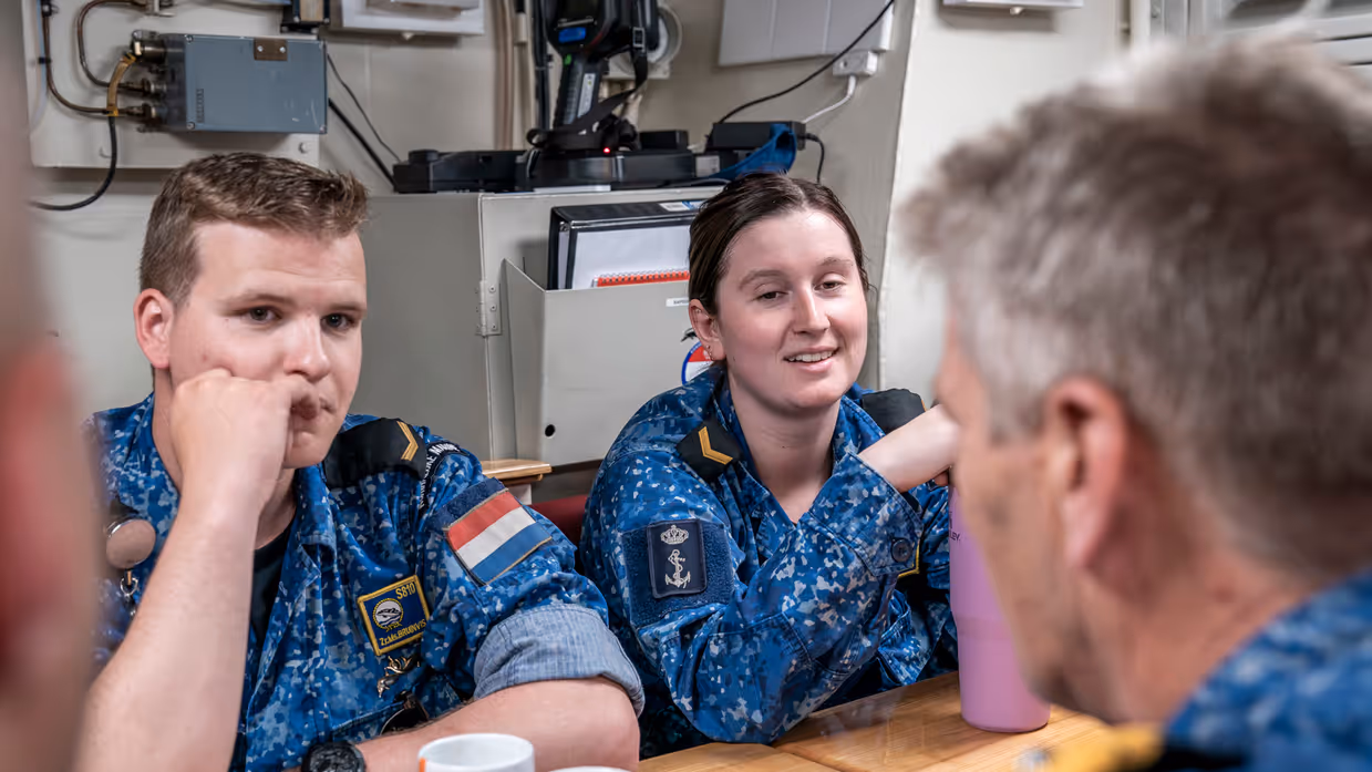 Vice-admiraal Boudewijn Boots is op een onderzeeboot aan tafel in gesprek met 2 matrozen.