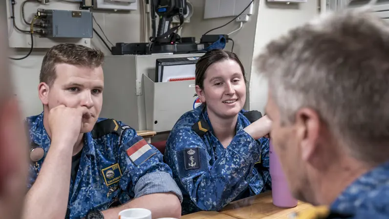 Vice-admiraal Boudewijn Boots is op een onderzeeboot aan tafel in gesprek met 2 matrozen.