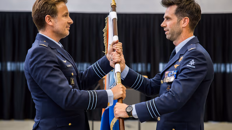 Jacobs overhandigt aan Hoogsteder op ceremoniële wijze een vlag.