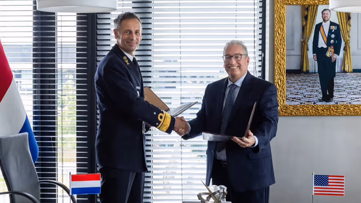 Militair en afgevaardigde bedrijf geven elkaar de hand na ondertekening overeenkomst.