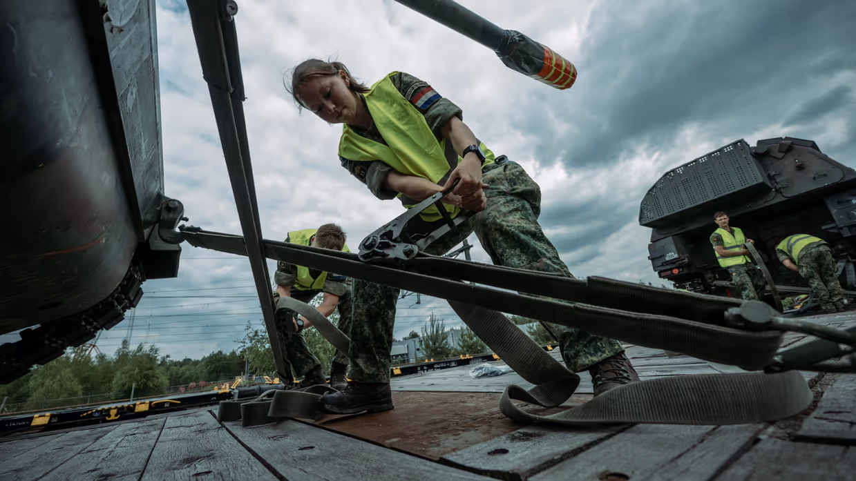 Militairen zetten zekeren militair voertuig voor vervoer per spoor.