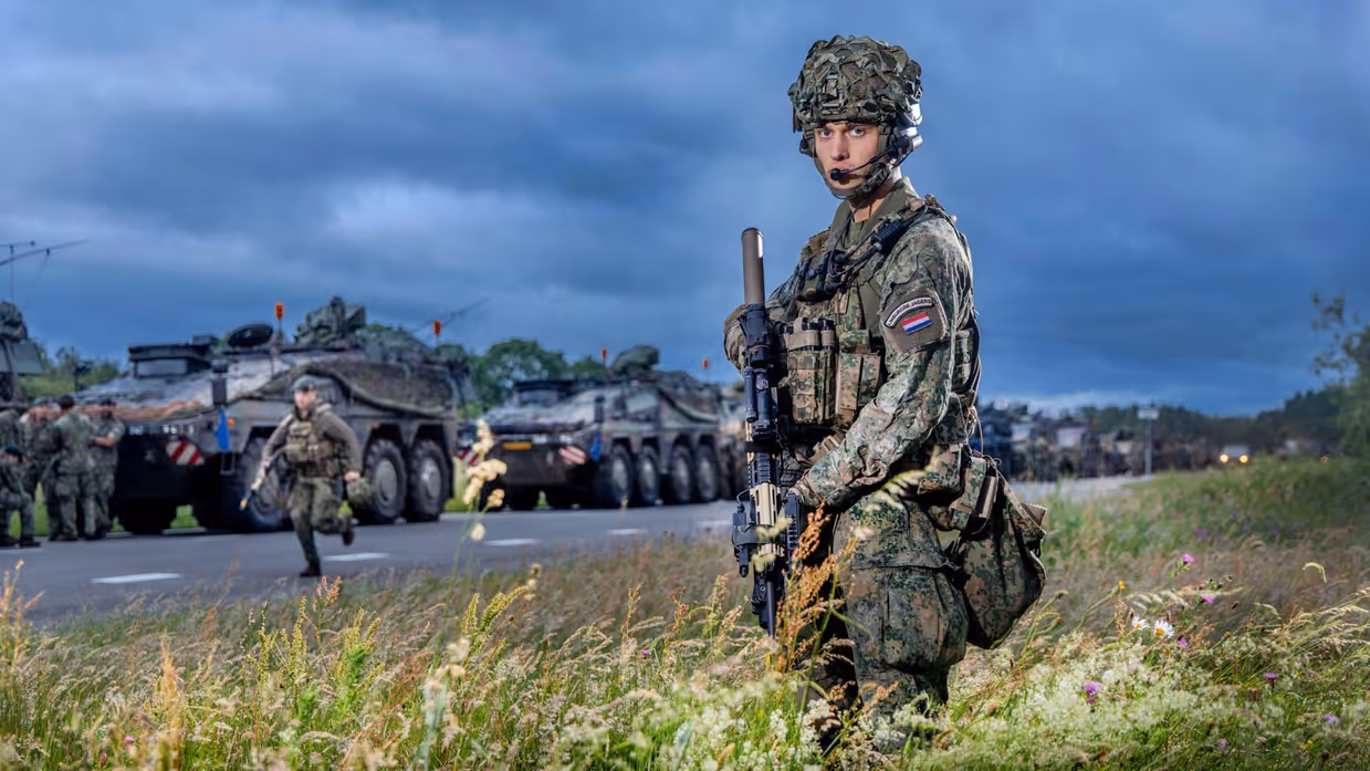 Soldaat eerste klasse Yuma staat langs een colonne militaire voertuigen vlak voor vertrek naar oefening Fighter Lion.
