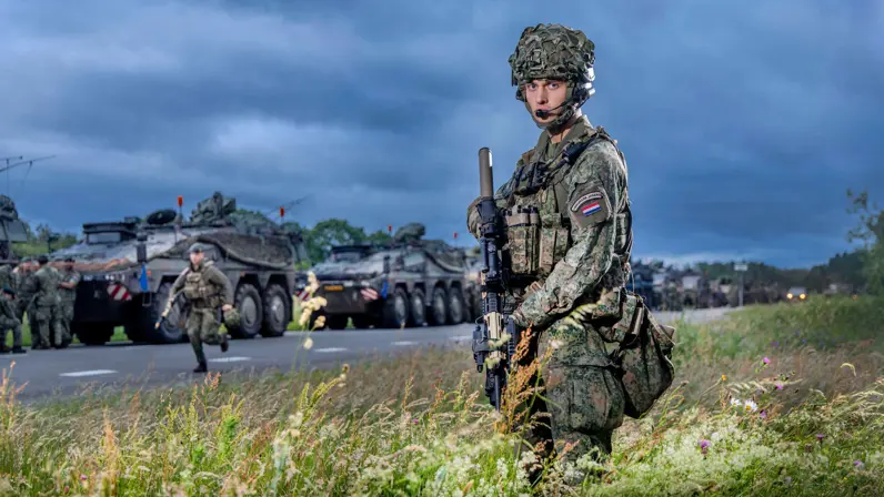 Soldaat eerste klasse Yuma staat langs een colonne militaire voertuigen vlak voor vertrek naar oefening Fighter Lion.
