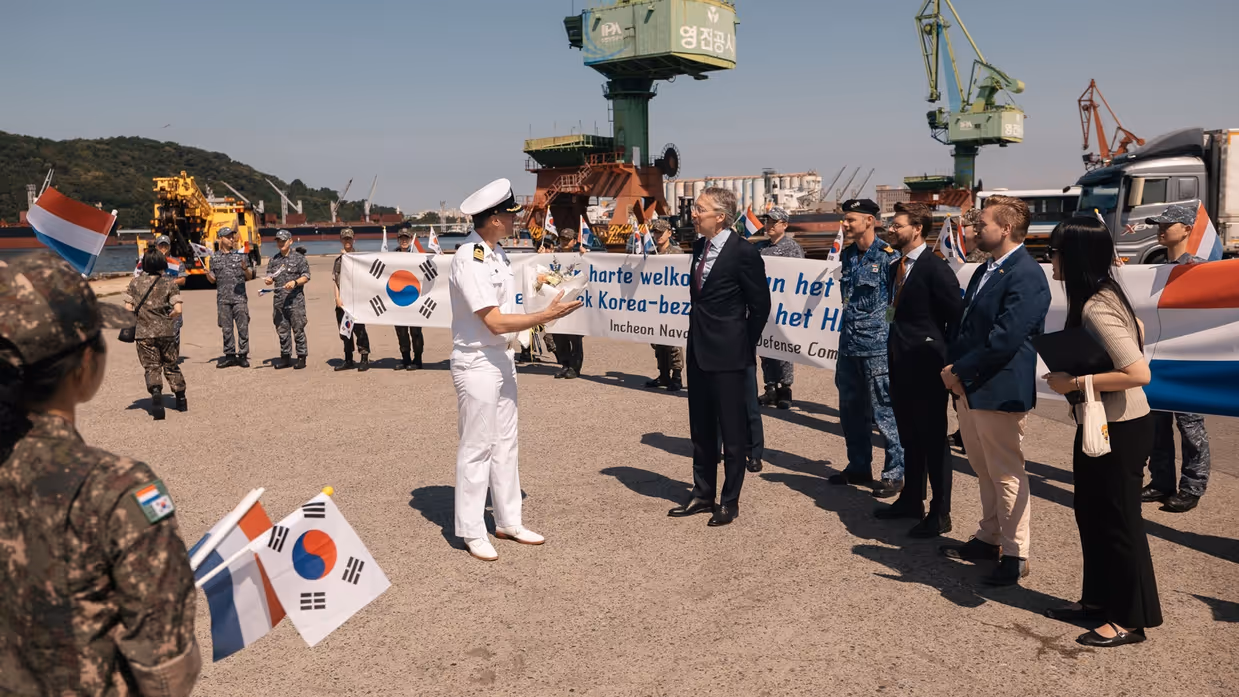 De commandant van de De Ruyter is de wal opgegaan en wordt hartelijk ontvangen door een grote delegatie met een spandoek en Koreaanse vlaggetjes.