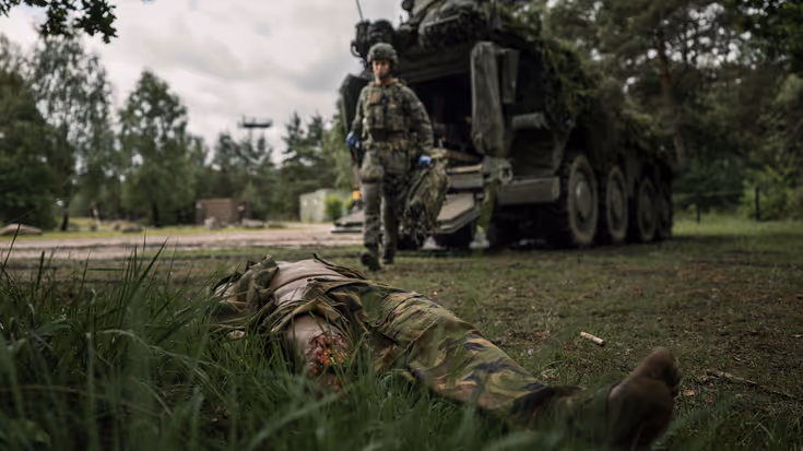 Een militairen loopt naar een gewonde collega.