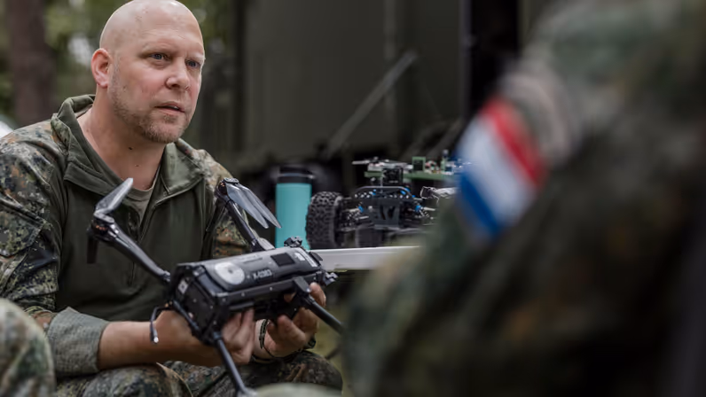 Kapitein Max van TechDevOps demonstreert tijdens oefening Fighter Lion een onbemand systeem aan collega-militairen.