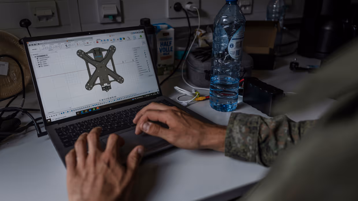 Een militair ontwerpt een nieuw onderdeel voor een drone op een laptop in de mobiele werkplaats van TechDevOps.