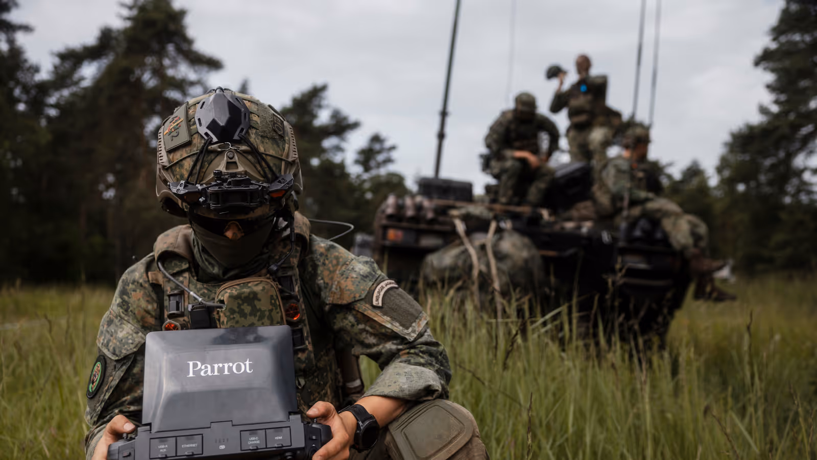 Een militair bereidt een dronevlucht voor tijdens oefening Fighter Lion, terwijl collega's op de achtergrond de operatie coördineren.