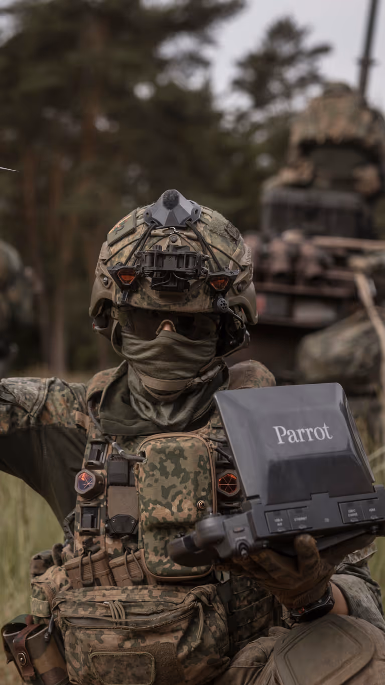 Een militair tijdens oefening Fighter Lion houdt een Parrot-verkenningsdrone omhoog terwijl hij de controller vasthoudt.