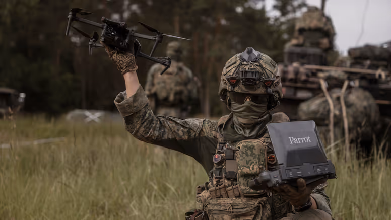 Een militair tijdens oefening Fighter Lion houdt een Parrot-verkenningsdrone omhoog terwijl hij de controller vasthoudt.