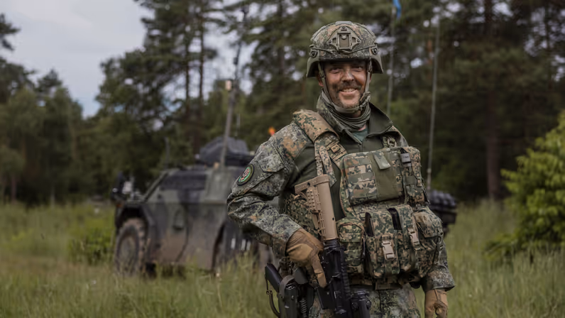 Luitenant-kolonel Marcel Kerstens staat tijdens oefening Fighter Lion voor een militair voertuig in een bosrijke omgeving.