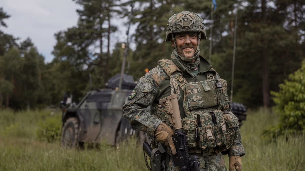 Luitenant-kolonel Marcel Kerstens staat tijdens oefening Fighter Lion voor een militair voertuig in een bosrijke omgeving.