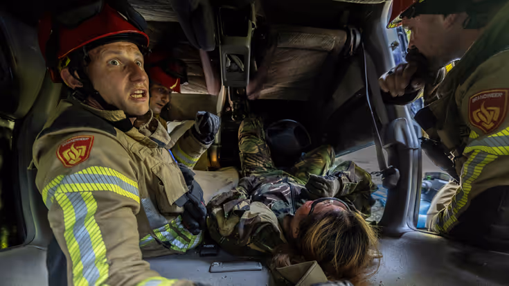 De brandweer probeert een bekneld iemand onder een auto te bevrijden.