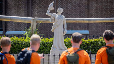 Studenten staan bij het monument te kijken