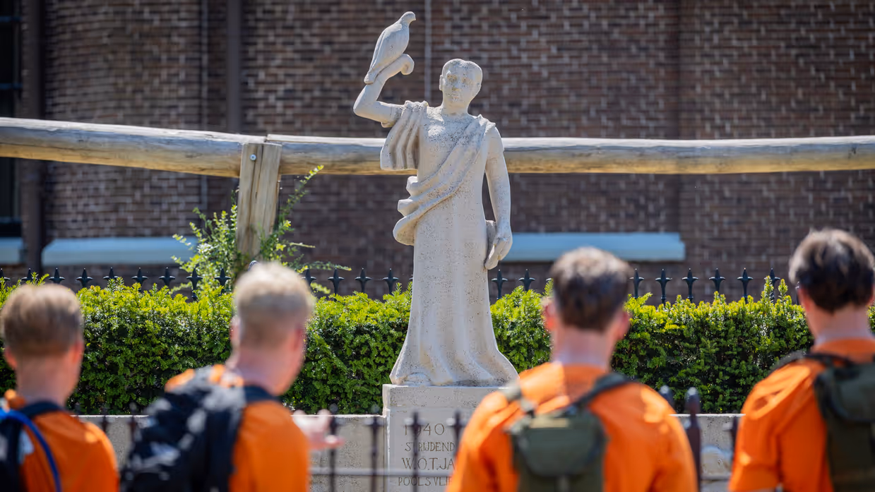Studenten staan bij het monument te kijken