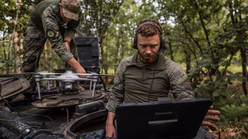 Eerste luitenant Jim werkt met een laptop terwijl korporaal Dylan een verkenningsdrone gereedmaakt voor een test van het AITAS-systeem tijdens oefening Fighter Lion.