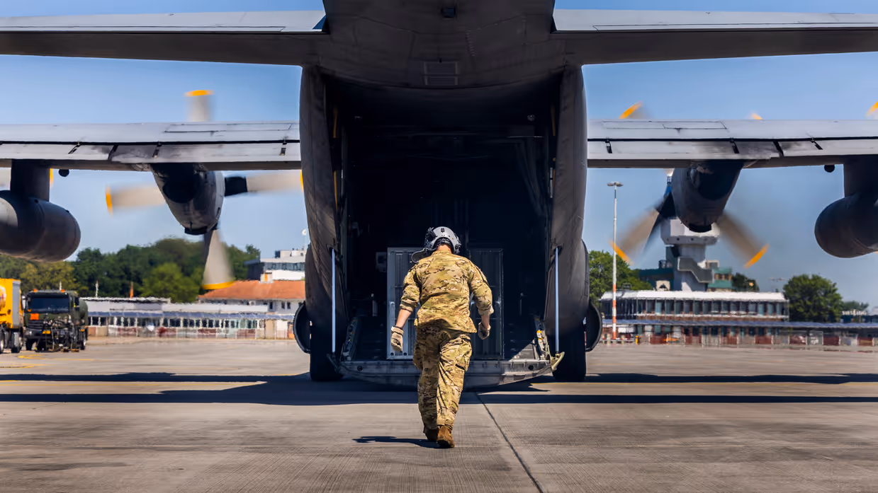 Militair loopt richting openstaande laadklep van C-130 Hercules-transportvliegtuig.